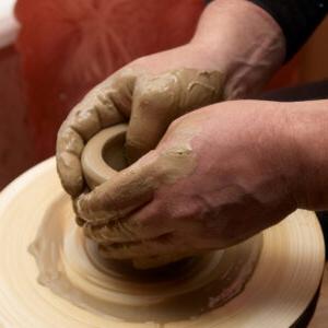 两只手在陶器轮上制作一个小锅